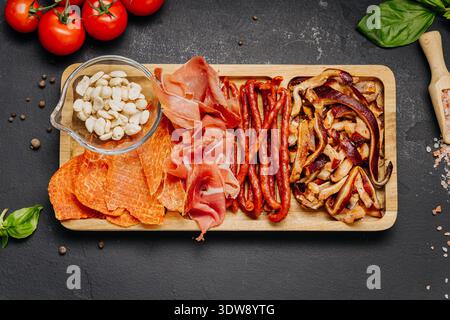 Assortiment de charcuteries et d'en-cas servis sur un plateau de hors-d'œuvre gastronomique en bois Banque D'Images