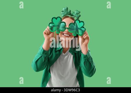 Rousse jeune femme avec décor en forme de trèfle sur fond vert. Célébration de la fête de Patrick Banque D'Images