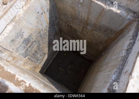 Regardant vers le bas dans un trou de béton profond, sombre et mystérieux. Une fosse vide, vieille ou abandonnée à la texture grunge, évoquant le sens du mystère et du confinem Banque D'Images