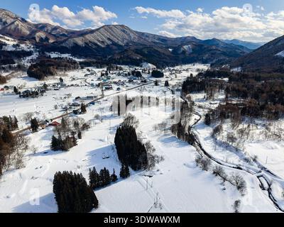 Vue aérienne pittoresque de la vallée enneigée avec rivière, arbres et montagnes en hiver Banque D'Images