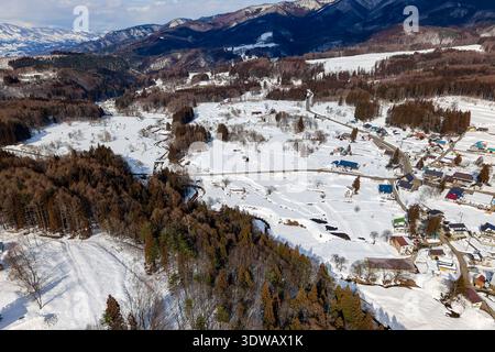Scène rurale de village japonais couverte de neige profonde avec des montagnes en arrière-plan Banque D'Images