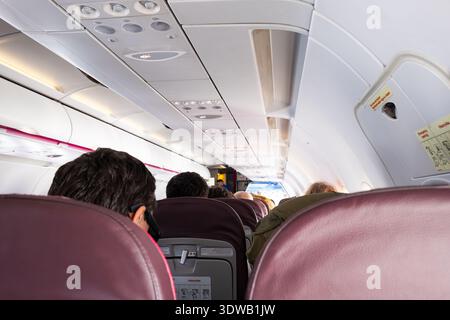 Bâle Euroairport, Suisse - 10 février 2026 : intérieur de cabine d'avion avec passagers assis en rangées avec compartiments supérieurs et cabine L. Banque D'Images