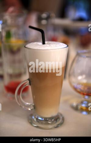 Dalgona, café mousseux dans un verre sur fond gris. Latte à boissons coréennes tendance avec mousse de café instantané. Gros plan. Banque D'Images