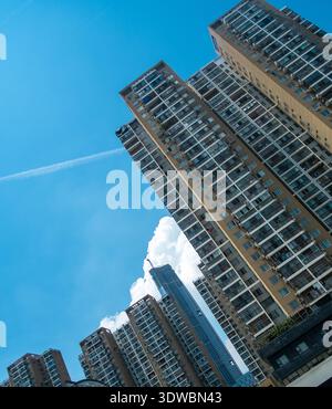Perspective à angle bas regardant les façades de grands immeubles résidentiels denses contre un ciel bleu avec une traînée de jet. Banque D'Images