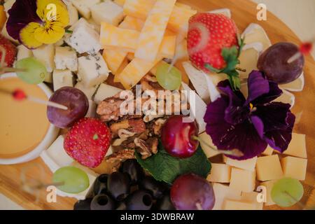 Une assiette avec assortiment de fromages, fruits, noix et miel Banque D'Images