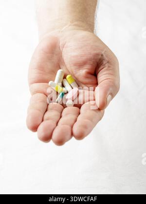 Main masculine avec des pilules sur fond clair. Différents médicaments sur le gros plan de la paume de l'homme ouvert. Pharmacologie et aide médicale co Banque D'Images