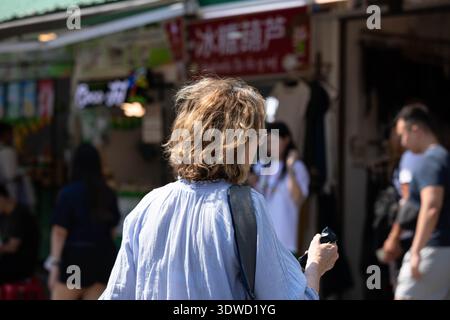 Femme marchant dans le marché local extérieur, seule dans la foule, personne solitaire dans la rue animée, vue arrière, au marché de Chatuchak. Banque D'Images