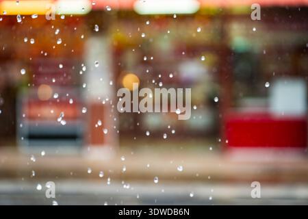 Gouttes de pluie à foyer doux avec fond de ville asiatique flou pendant la saison de mousson. Soft Focus pluie tropicale urbaine, humidité. Climat pluvieux, voyage Banque D'Images