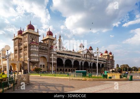 Majestueux palais Mysore dans le Karnataka, en Inde, avec une architecture indo-saracénique avec des dômes rouges, des arches ornées, des tours et des jardins paysagers Banque D'Images