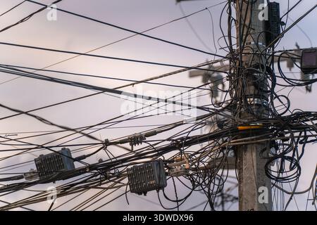 Une vue rapprochée de fils électriques enchevêtrés sur un poteau de service, mettant en évidence la complexité et l'organisation de l'infrastructure urbaine moderne contre un CLO Banque D'Images