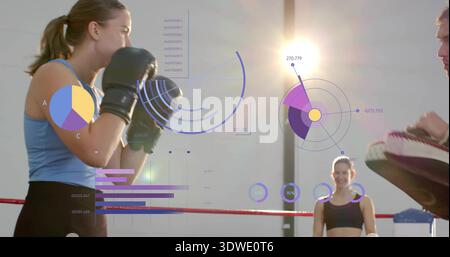 Lancer un punch, boxer féminin en débardeur bleu clair à l'intérieur de l'anneau ganté, entraîneur avec des mitaines, HUD Banque D'Images