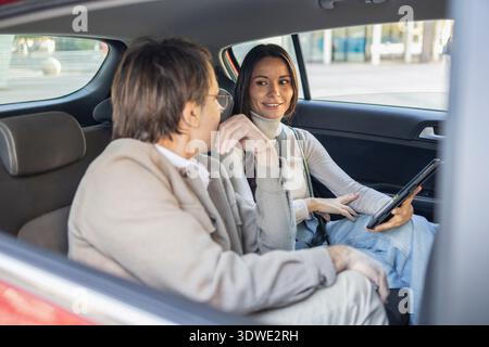 Un couple aime une conversation détendue à l'intérieur de leur voiture lors d'un voyage panoramique. L'homme écoute attentivement tandis que la femme partage quelque chose, créant une joie Banque D'Images