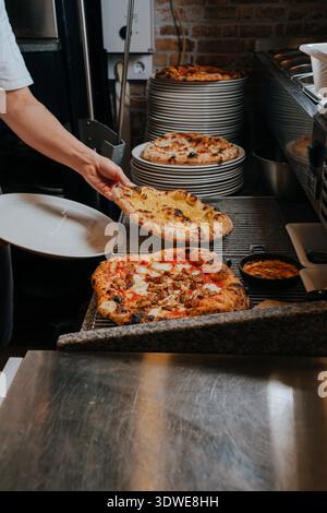 Un chef expérimenté prépare habilement une pizza napolitaine faite à la main dans un cadre confortable et rustique pizzeria. La croûte dorée et les ingrédients frais créent une bouche Banque D'Images