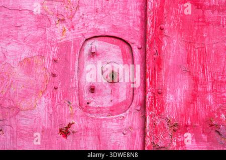 Gros plan d'une porte rose altérée avec de la peinture pelable texturée et de la rouille visible, mettant en valeur une esthétique vieillie à Taiwan. L'image capture le charme o Banque D'Images
