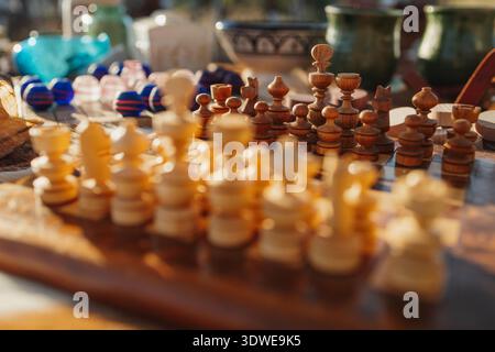 Un jeu d'échecs médiéval magnifiquement conçu entouré de divers objets vintage et de verrerie colorée, mettant en valeur l'artisanat historique complexe. Banque D'Images