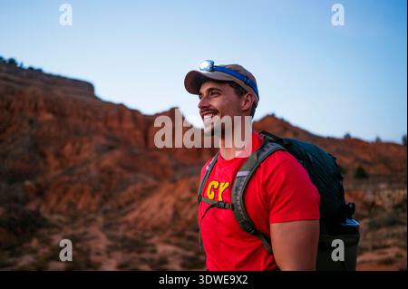 Un homme en chemise rouge se tient devant un canyon rouge à couper le souffle en Espagne, mettant en valeur la beauté naturelle sauvage et les couleurs vibrantes de ce pays unique Banque D'Images