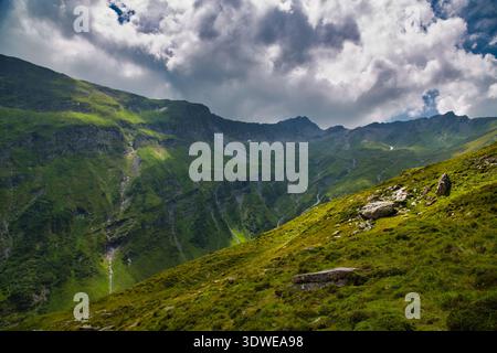Vue imprenable sur Greina, Suisse, avec des montagnes vertes luxuriantes et un ciel spectaculaire. Banque D'Images