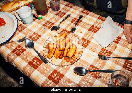 Un plat traditionnel de bandes de poitrine de porc frites repose sur une plaque de verre placée sur une nappe à carreaux, évoquant un sentiment de repas rustique rural et cher Banque D'Images