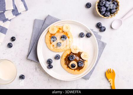 Profitez d'un délicieux petit déjeuner composé de crêpes moelleuses garnies de bleuets frais et de tranches de bananes. Une friandise matinale parfaite pour bien commencer la journée Banque D'Images