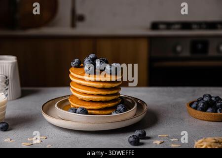 Délicieux petit déjeuner avec une pile de crêpes moelleuses surmontées de myrtilles fraîches sur une table rustique. Parfait pour un mea matinal confortable Banque D'Images