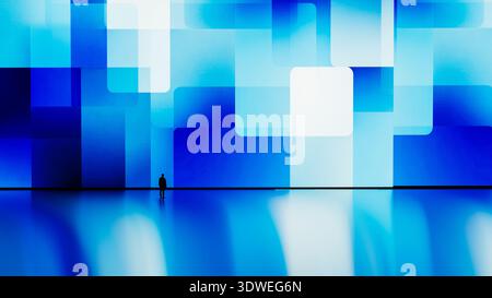 Un homme se tient immobile devant un grand écran numérique affichant des formes géométriques bleues. Banque D'Images