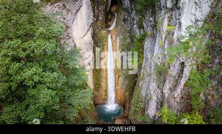 Une vue imprenable sur la cascade de Grandvillard en cascade entre les falaises rocheuses en Suisse, entourée d'une végétation luxuriante, capturant l'essence de l'unisson Banque D'Images