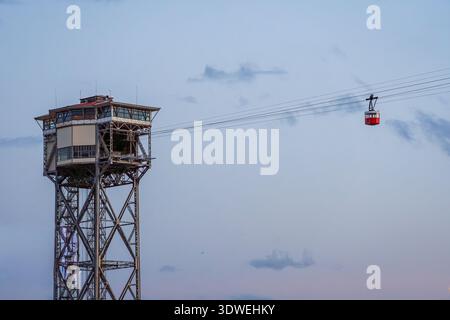 Un téléphérique moderne traverse un horizon urbain au crépuscule, avec un ciel calme et une tour d'acier comme toile de fond. Le paysage urbain est placé contre un e clair et bleu Banque D'Images