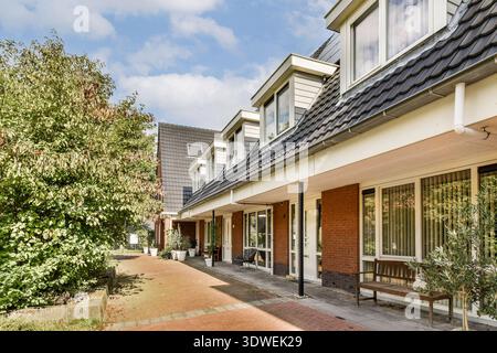 Une vue sur un immeuble résidentiel contemporain avec un jardin et une allée bien entretenus, mettant en valeur un design élégant et un aménagement paysager. Banque D'Images