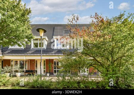Une maison résidentielle moderne met en valeur son architecture contemporaine entourée d'une verdure vibrante et d'un ciel bleu clair. Banque D'Images
