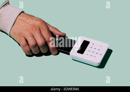 Une image en gros plan d'une main actionnant un lecteur de carte élégant, mettant en évidence la technologie moderne dans les solutions de paiement sans contact, mettant l'accent sur la commodité et Banque D'Images