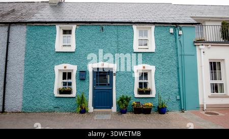 Un charmant cottage bleu et blanc dans le pittoresque Ring of Kerry, Irlande. Des pots de fleurs lumineux ornent la porte, ajoutant une couleur vibrante à ce quain Banque D'Images