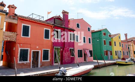 Des façades vibrantes et colorées bordent un canal serein à Burano, Venise, Italie. Les charmantes maisons reflètent un arc-en-ciel de couleurs, ajoutant du caractère à ce pict Banque D'Images