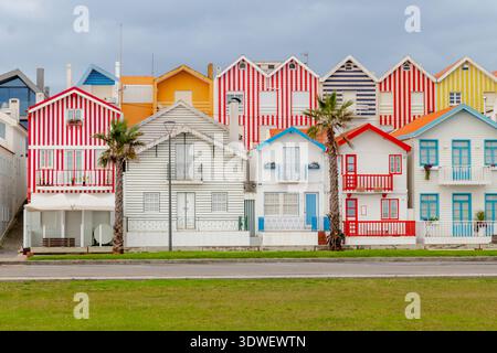 Des maisons rayées vibrantes bordent la rue de Costa Nova, au Portugal, mettant en valeur un mélange d'architecture traditionnelle et de couleurs audacieuses contre un coasta serein Banque D'Images