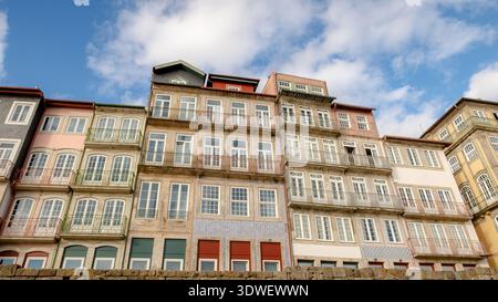 Des bâtiments dynamiques aux façades colorées et aux carreaux complexes bordent le quartier historique de Cais da Ribeira, offrant une vue pittoresque sur le Douro Banque D'Images