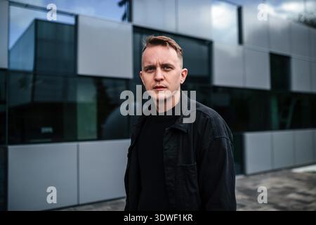 Portrait élégant d'un jeune designer masculin debout avec confiance sur fond d'architecture moderne à Kiev, en Ukraine, mettant en valeur la mode urbaine Banque D'Images