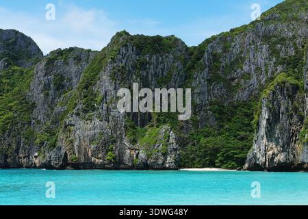 Les falaises rocheuses à la végétation dense surplombent les eaux turquoises claires et une plage de sable en Thaïlande, mettant en valeur le magnifique paysage côtier de l'ARE Banque D'Images