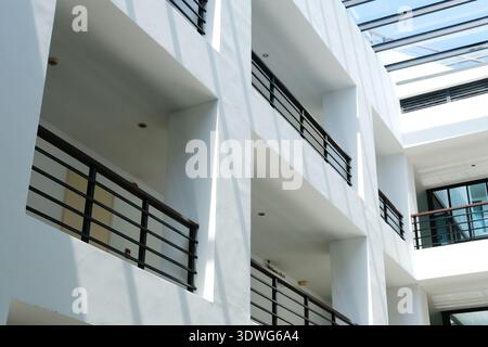 L'intérieur du bâtiment contemporain présente des murs blancs et des balustrades noires sur les balcons, illuminé par la lumière naturelle qui traverse de grandes fenêtres Banque D'Images