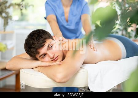 Masseuse faisant un massage du dos au jeune gars Banque D'Images