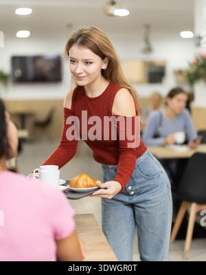 Femme avec deux tasses de café sur le plateau va à la table dans le café, ayant une pause café avec des amis, des collègues Banque D'Images