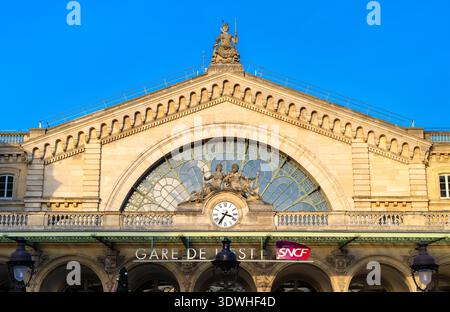 Paris, France - 16 décembre 2025 : vue panoramique ensoleillée sur la façade historique en pierre classique, l'horloge et les statues de la gare de l'est. Banque D'Images