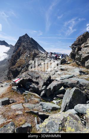 Randonneurs se reposant sur un sentier de montagne rocheux au sommet du Col de Prafleuri sur la haute route, Valais, Suisse. Banque D'Images