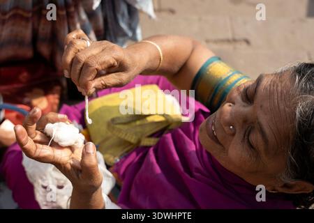 Une femme âgée de Varanasi, en Inde, file habilement du fil de coton à la main dans une tenue traditionnelle. Banque D'Images
