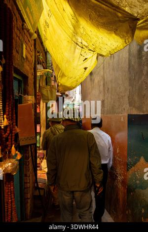 Les gens marchent dans une ruelle étroite couverte d'une bâche jaune à Varanasi, en Inde. Banque D'Images