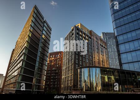 Tours résidentielles et commerciales modernes près de Deansgate, Manchester, avec la flèche de la cathédrale de Manchester reflétée dans le vitrage incurvé. Banque D'Images