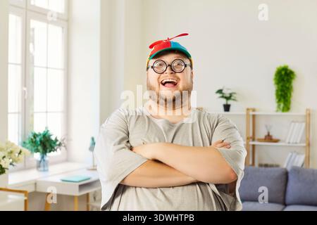 Homme joyeux de grande taille en bonnet à hélice et lunettes nerd avec les bras croisés Banque D'Images