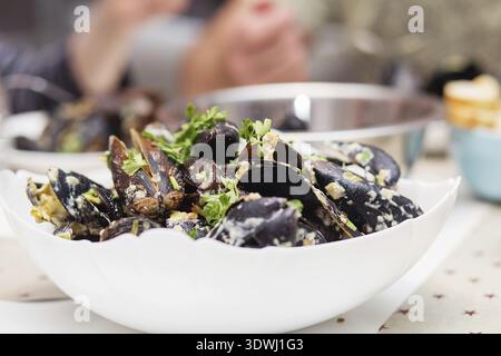 Moules cuites à la vapeur dans une sauce au fromage. Moules en coquilles dans le bol avec du vin blanc sur la table Banque D'Images