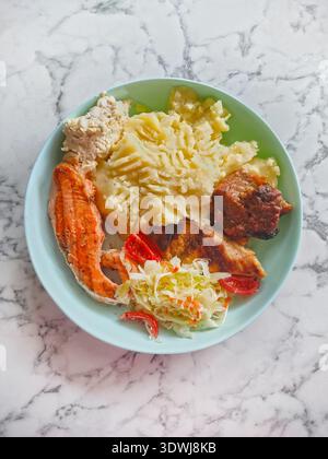 portion de nourriture maison sur plaque turquoise debout sur une surface en marbre. Purée de pommes de terre, poisson cuit au four, saumon. Viande frite, porc, côtes levées, sala de légumes Banque D'Images