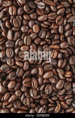 Grains de café noirs en studio. Grains de café fraîchement torréfiés comme fond de texture Banque D'Images