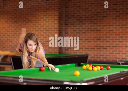 Femme visant tiré sur la salle de billard penchée au-dessus de la table de billard tenant le bâton de queue par boule de queue. Joueur, concentration, loisirs, loisirs, loisirs, brick, je Banque D'Images