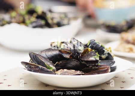 Moules cuites à la vapeur dans une sauce au fromage. Moules en coquilles dans le bol avec du vin blanc sur la table Banque D'Images